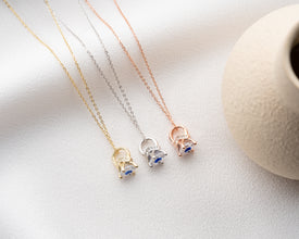 A handcrafted silver claw necklace holding a shimmering blue crystal, symbolizing intuition and positivity.