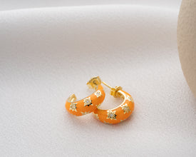 Sunset hoop earrings styled on black background for dramatic effect