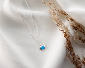 A minimalist sterling silver bird pendant with an opal charm, perfect for layering.