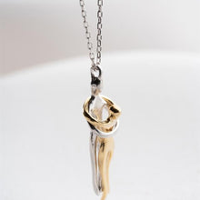 Two-tone gold and silver pendant on a chain against a light background