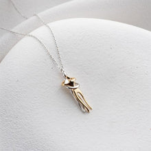 Gold necklace with a pendant on a textured white surface