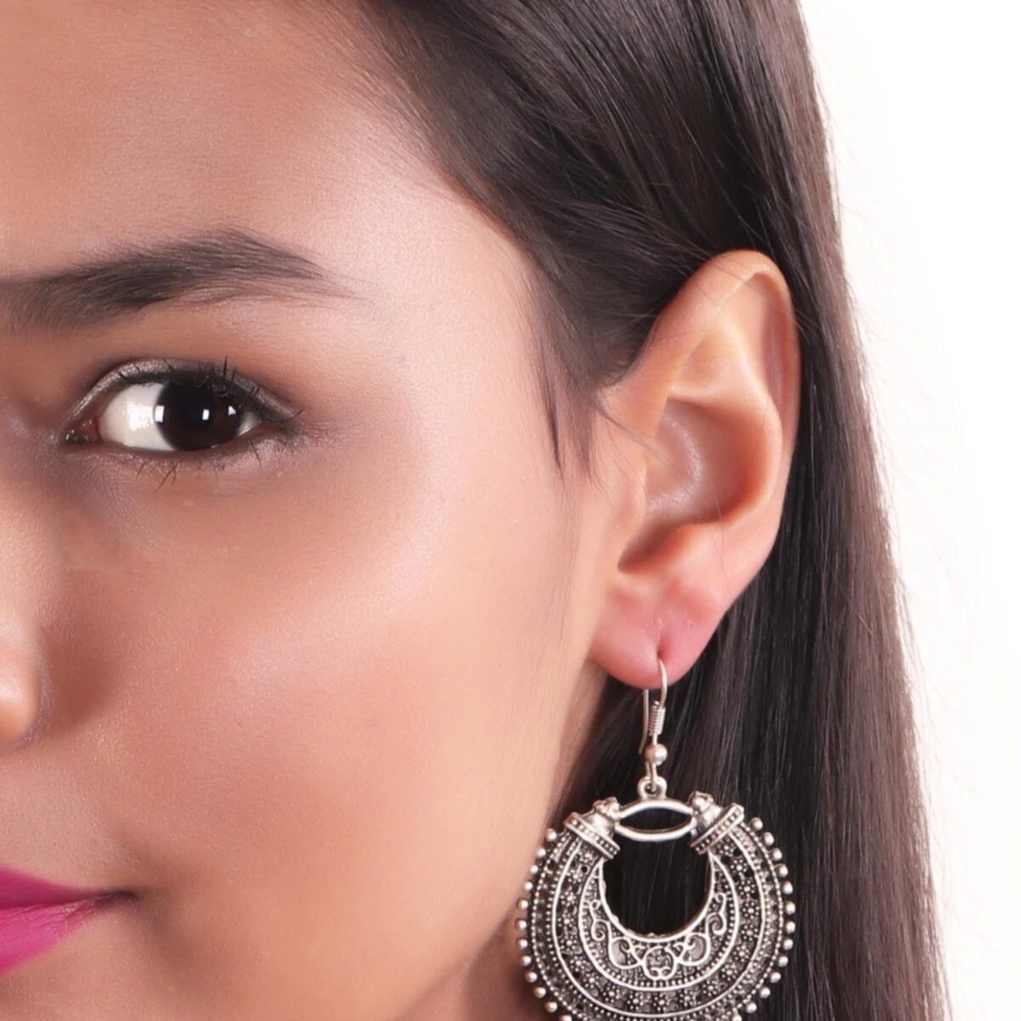 Close-up of a woman wearing a silver and black earring on a white background