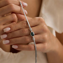 Silver bracelet with a green gemstone held by a person's hand.