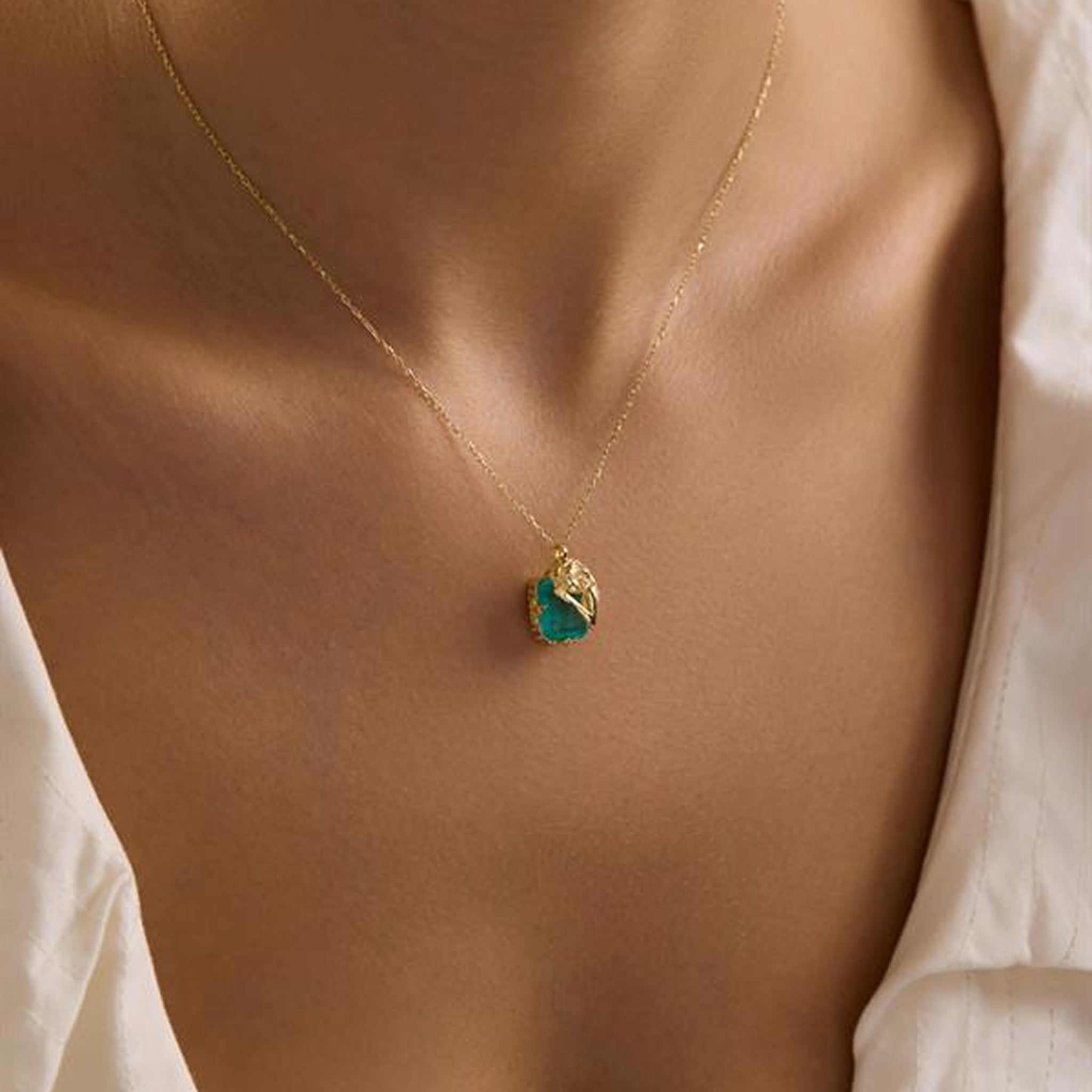 Necklace with a green pendant on a person wearing a white shirt
