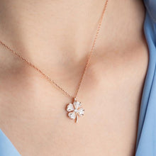 Rose gold necklace with a diamond pendant on a person wearing a light blue top.