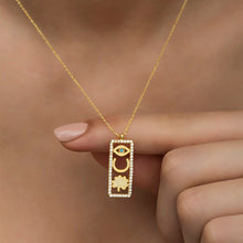 Gold necklace with a rectangular pendant featuring an eye design on a blurred background