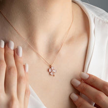 Necklace with a floral pendant worn by a person, close-up of the necklace on skin.