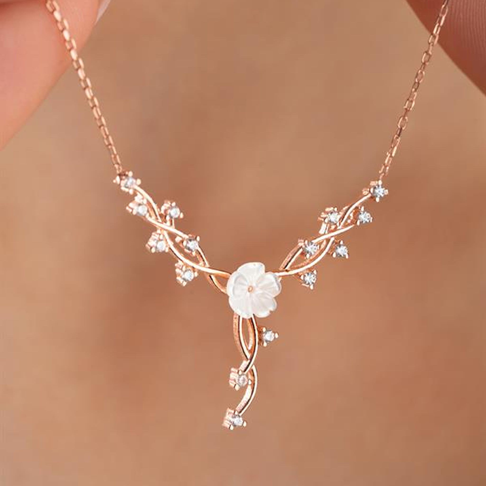 Delicate rose gold necklace with a floral design on a blurred background