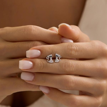 Silver cat-shaped earrings on a person's hand with a neutral background