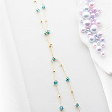 Gold necklace with blue beads on a white surface
