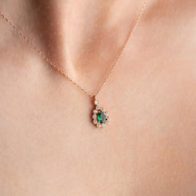 Rose gold necklace with a green gemstone pendant on a person's neck.