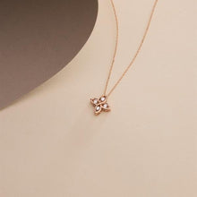 Rose gold necklace with a floral pendant on a beige background