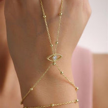 Gold anklet with eye design on a person's ankle against a blurred background