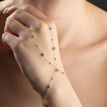 Gold anklet with blue beads on a person's ankle against a neutral background