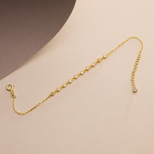Gold chain bracelet on a beige background