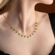 Gold necklace with green gemstones worn by a person