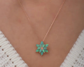 Close-up of a dainty fire opal lotus pendant with a delicate silver chain.