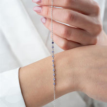 Silver bracelet with blue stones on a wrist against a white background