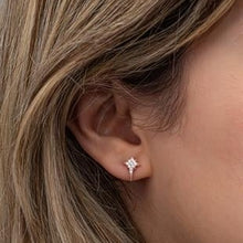 Close-up of an ear wearing a diamond stud earring with blonde hair.