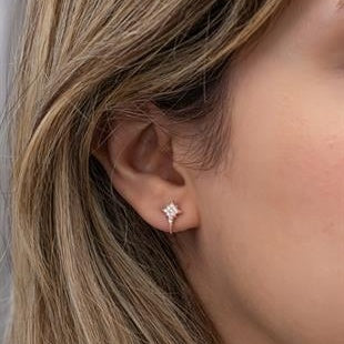 Close-up of an ear wearing a silver star-shaped earring with blonde hair.