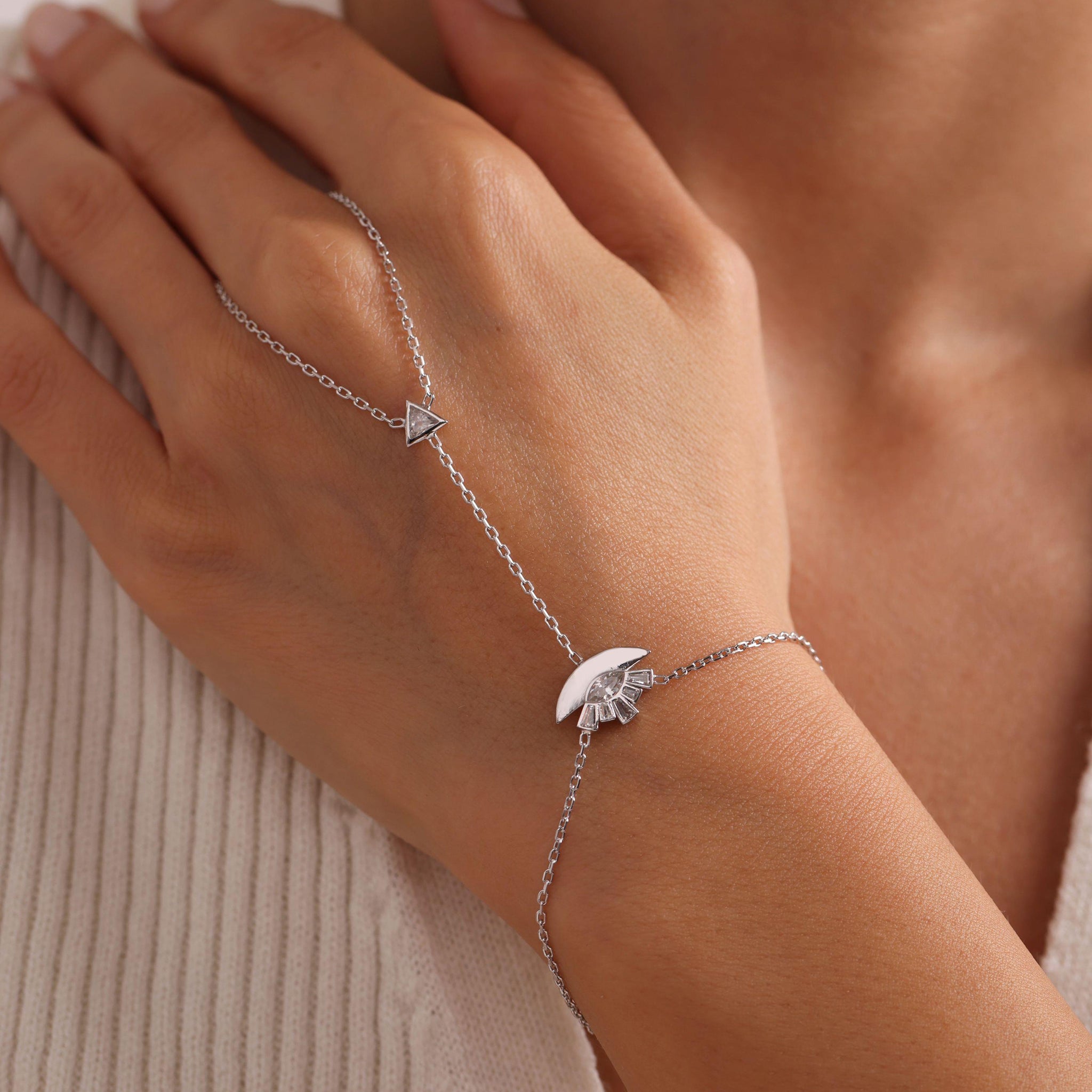 Silver bracelet with a moon and star design on a wrist against a neutral background