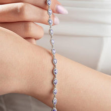 Silver bracelet with clear stones on a wrist against a neutral background