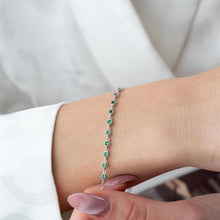 Silver bracelet with green gemstones on a person's wrist against a white background