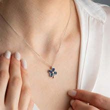 Necklace with a blue flower pendant worn by a person