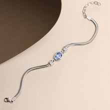 Silver bracelet with a blue gemstone on a beige background