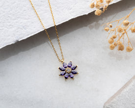 Handmade botanical jewelry featuring a floral charm with a radiant amethyst accent.