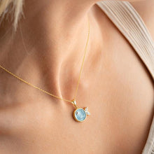 Gold necklace with a blue pendant on a person's neck