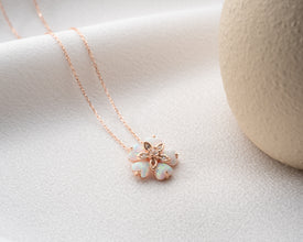 Handmade botanical-inspired jewelry featuring a sterling silver flower pendant with an opal gemstone.