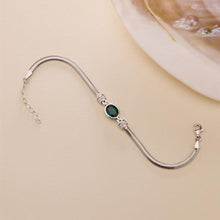 Silver bracelet with a green gemstone on a beige background