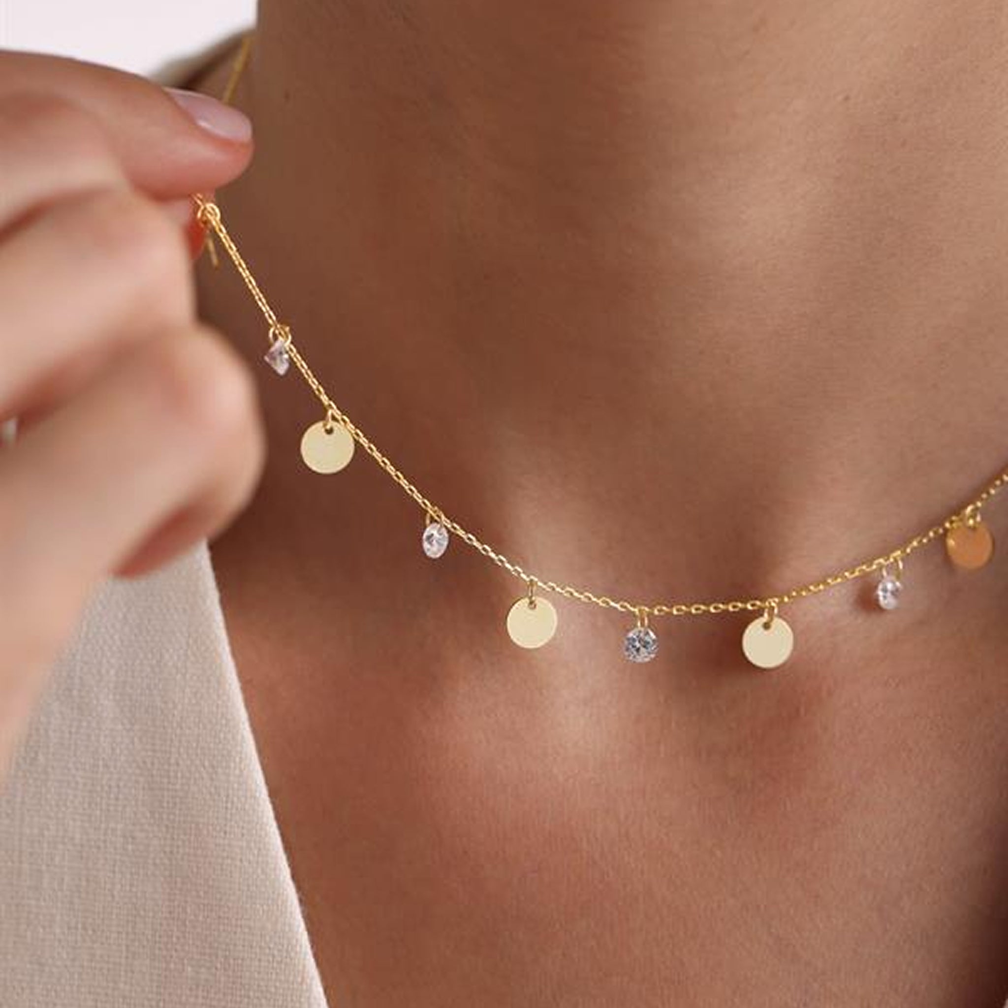 Gold necklace with small pendants on a person's neck