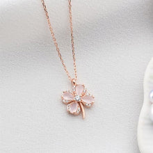 Rose gold necklace with a clover-shaped pendant on a light gray background