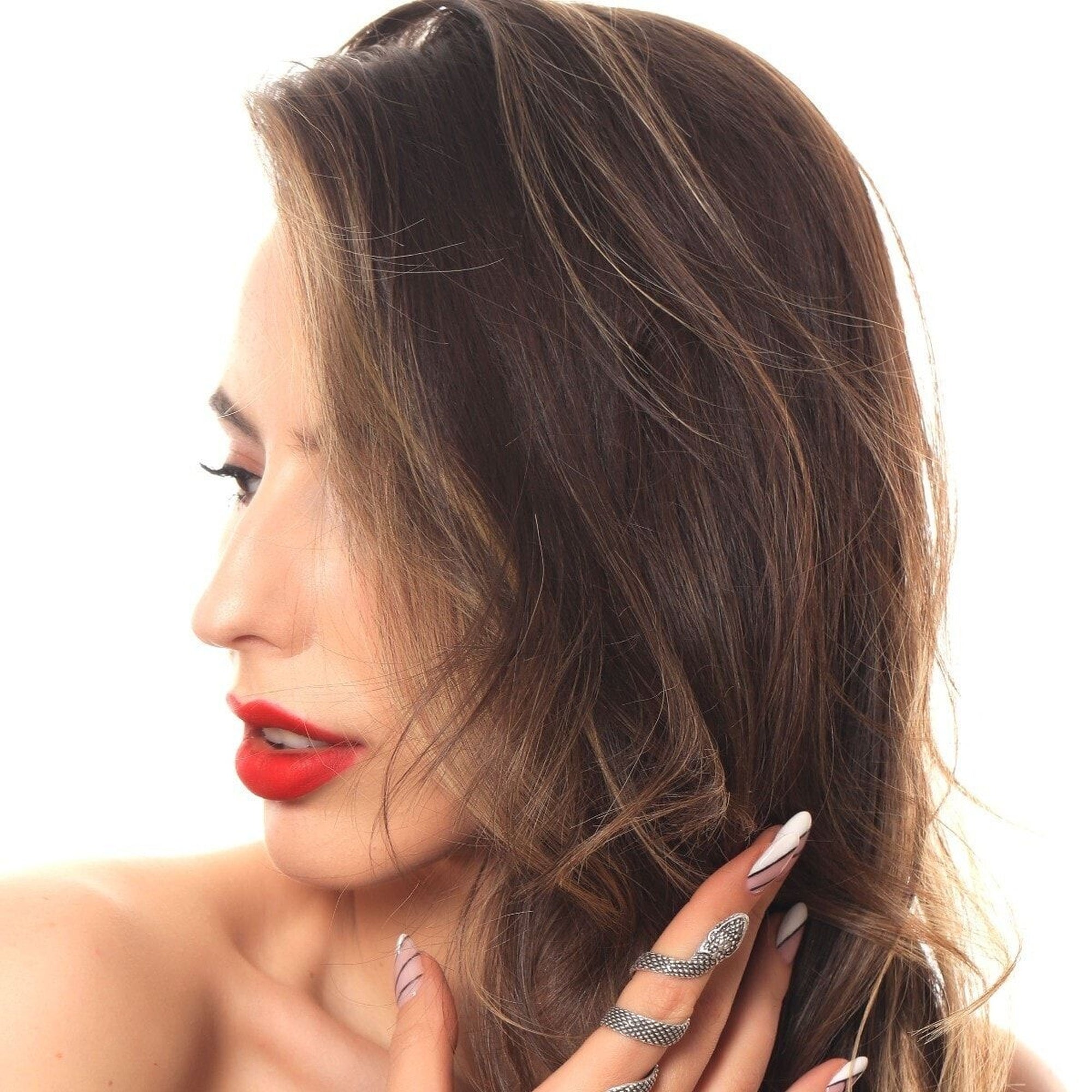 Close-up of a woman with red lipstick and a hand near her face on a white background