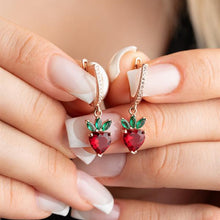 Rose gold earrings with red gemstones held between fingers