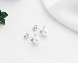 Silver earrings on a white surface with a minimal background