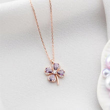 Rose gold necklace with a clover-shaped pendant on a light gray background
