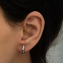 Close-up of an ear wearing a small hoop earring with a blurred background