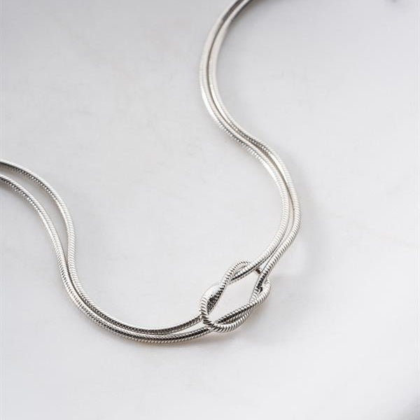 Silver necklace on a light gray background