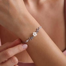 Close-up of a wrist wearing a delicate bracelet with a floral design.