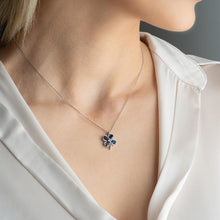 Necklace with a floral pendant worn by a person in a white shirt