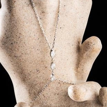 Silver necklace with a pendant on a mannequin hand against a black background