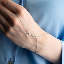 Hand wearing a delicate silver bracelet with a blue shirt in the background