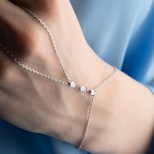 Silver anklet on a person's ankle with a blurred blue background