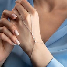 Close-up of hands with a delicate silver bracelet on a soft blue background