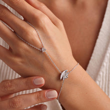 Silver bracelet with a star-shaped clasp on a wrist against a neutral background