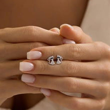 Pair of silver cat-shaped earrings on a person's hand with a neutral background