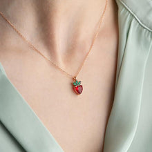 Necklace with a strawberry pendant worn by a person in a light green outfit.